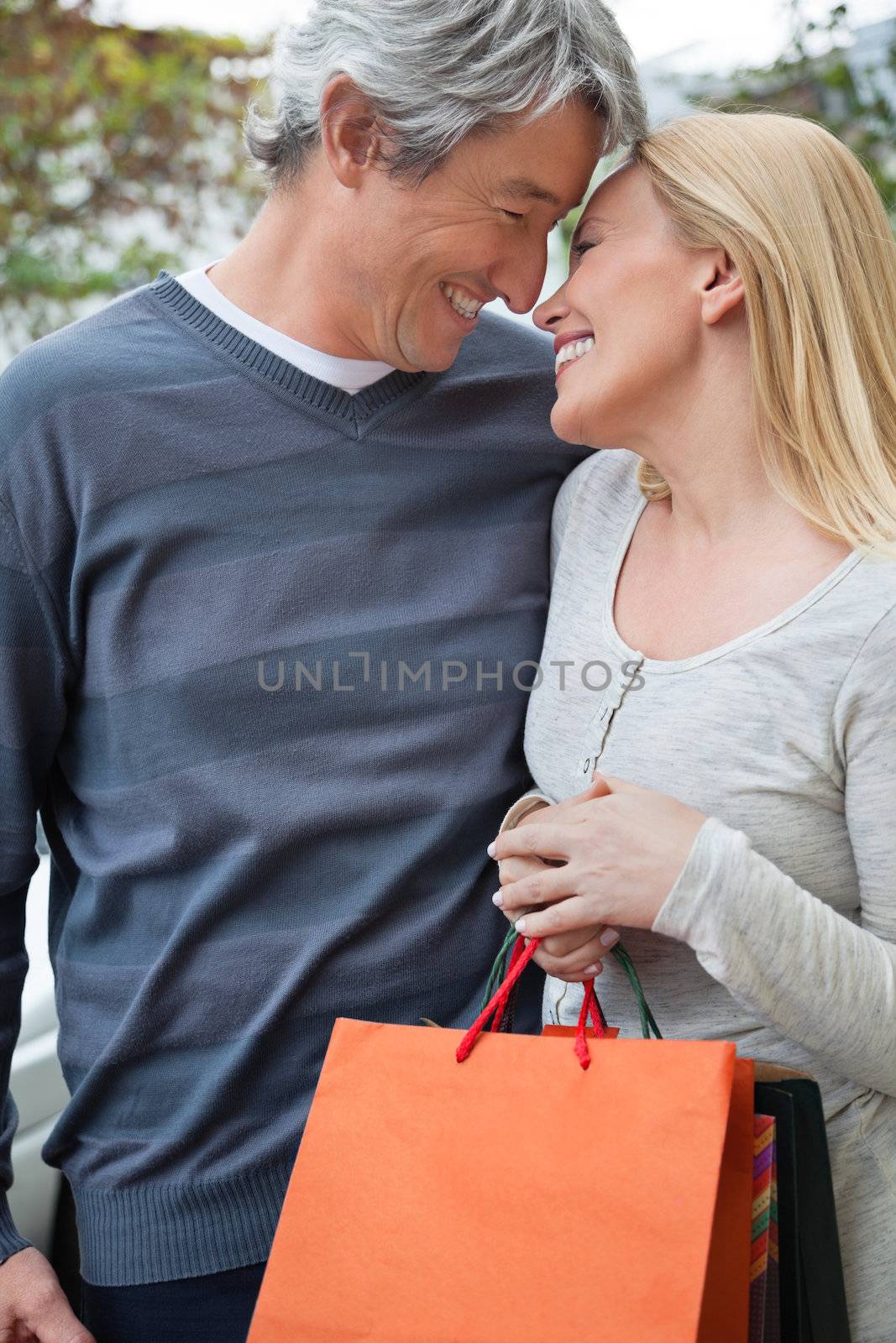 Romantic couple looking at each other as woman holds shopping bags