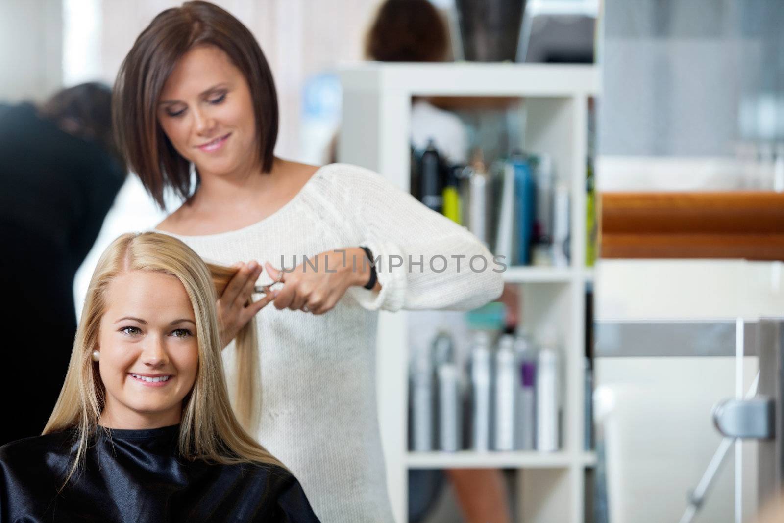 Mirror reflection of hairdresser giving a haircut to woman at parlor