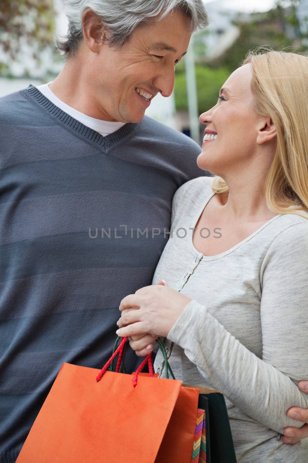 Happy couple looking at each other as woman holding shopping bags