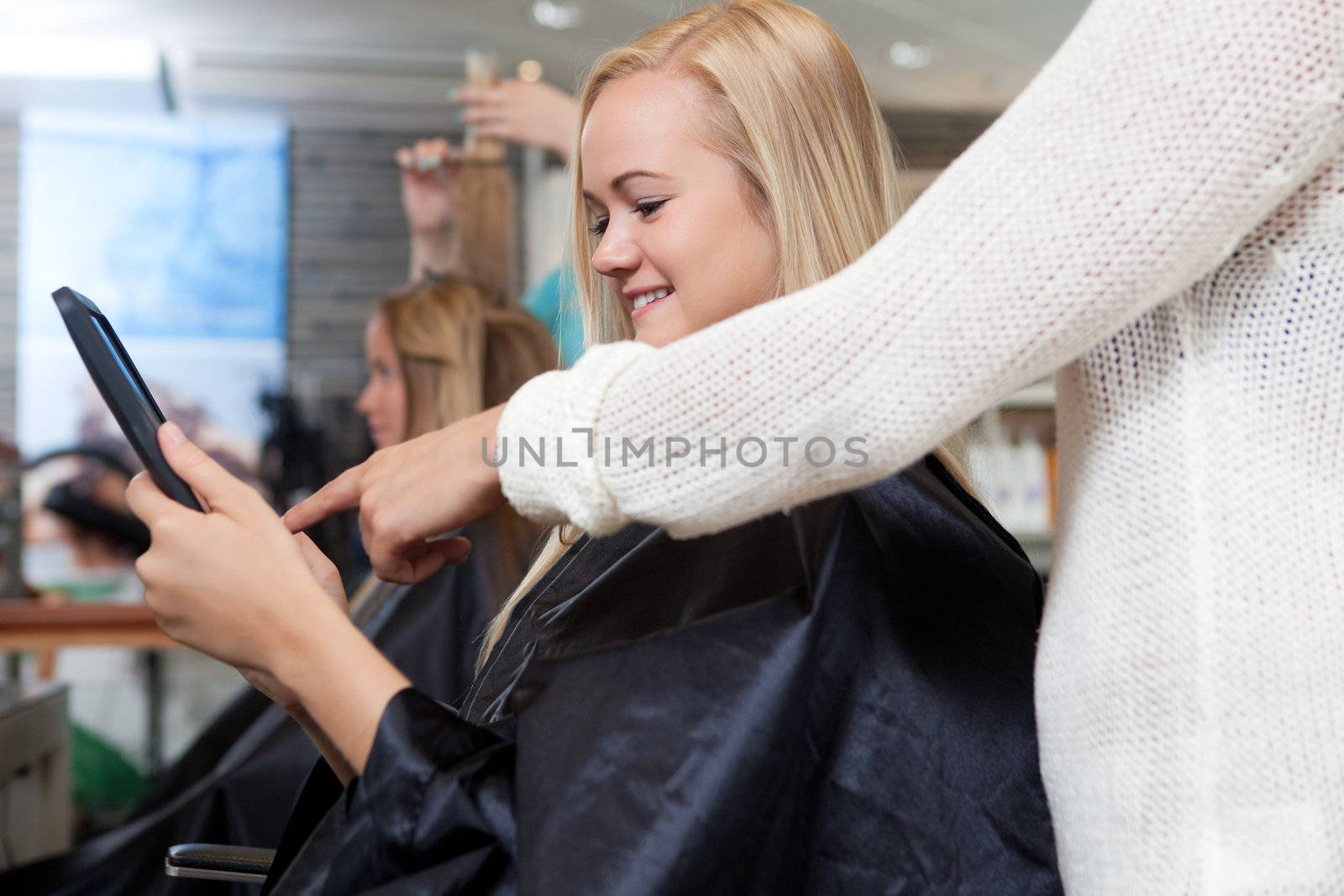 Customer showing hair dresser an image on a digital tablet.