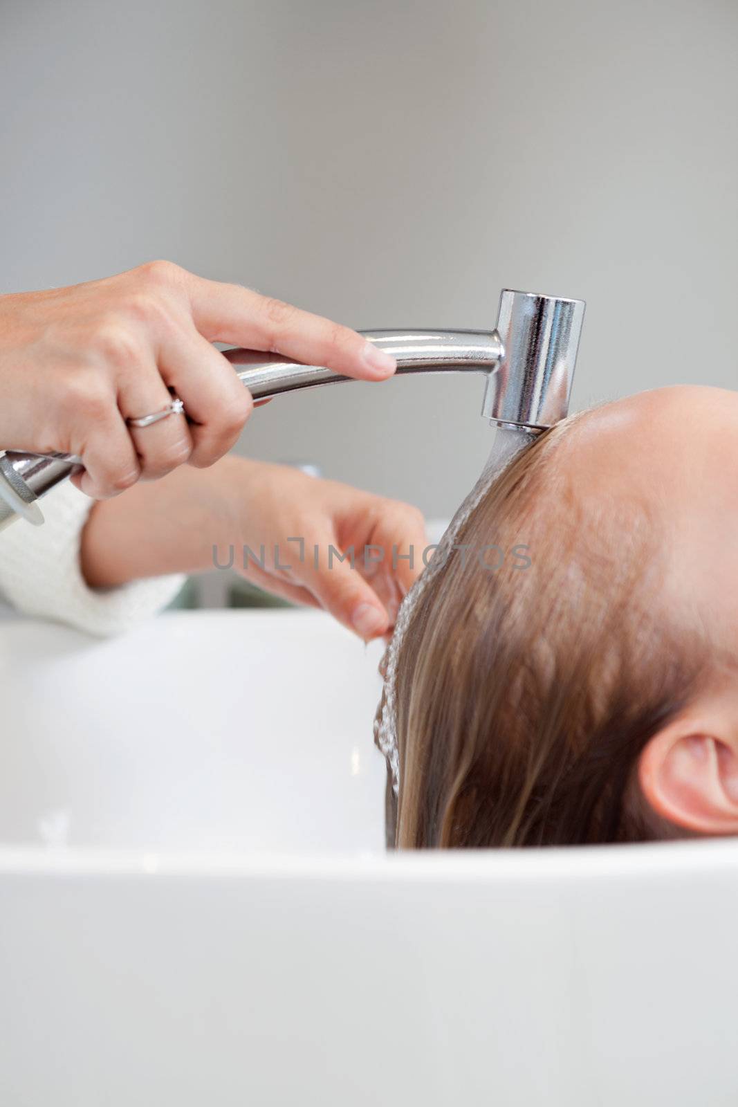 Cropped image of beautician washing hair of female customer at beauty salon