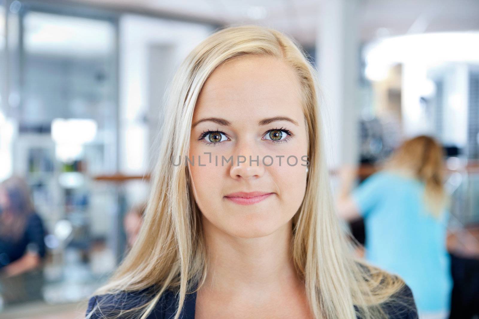 Close up portrait of a blonde young female owner of beauty parlor smiling