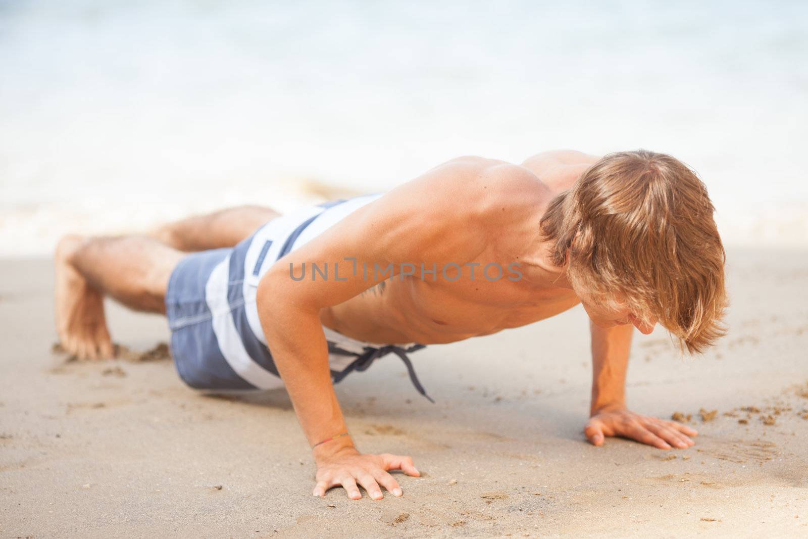 youn man making exercise on the beach by Lcrespi