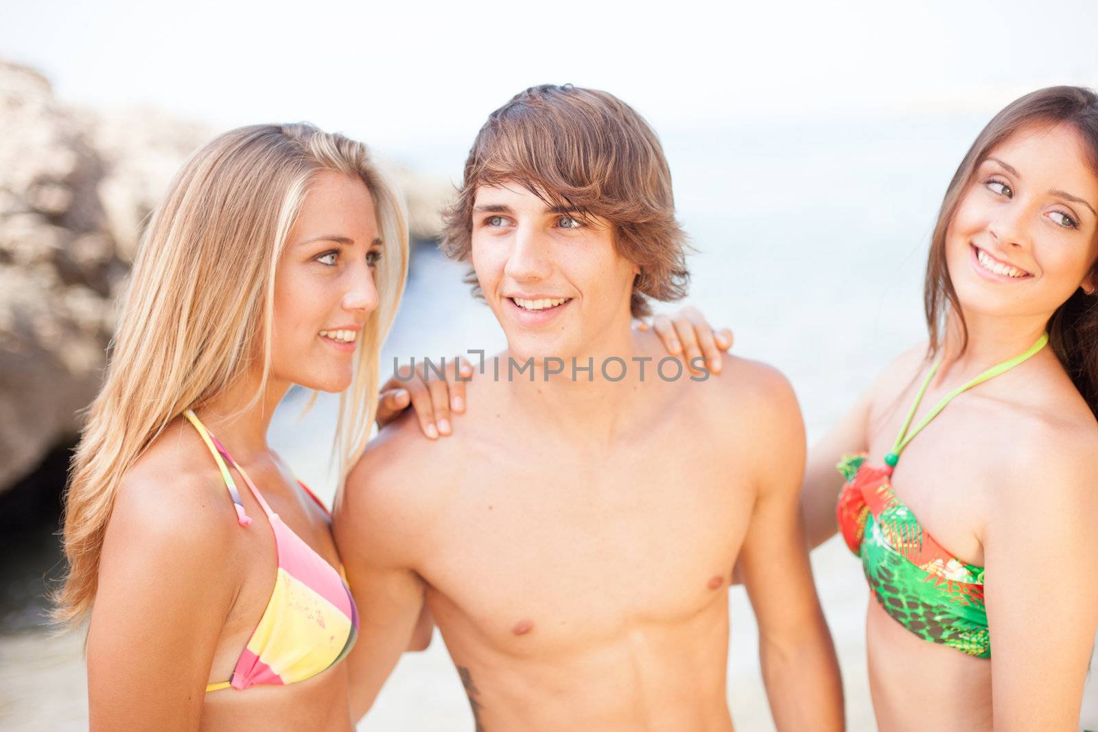 three young beautiful friends having fun on the beach