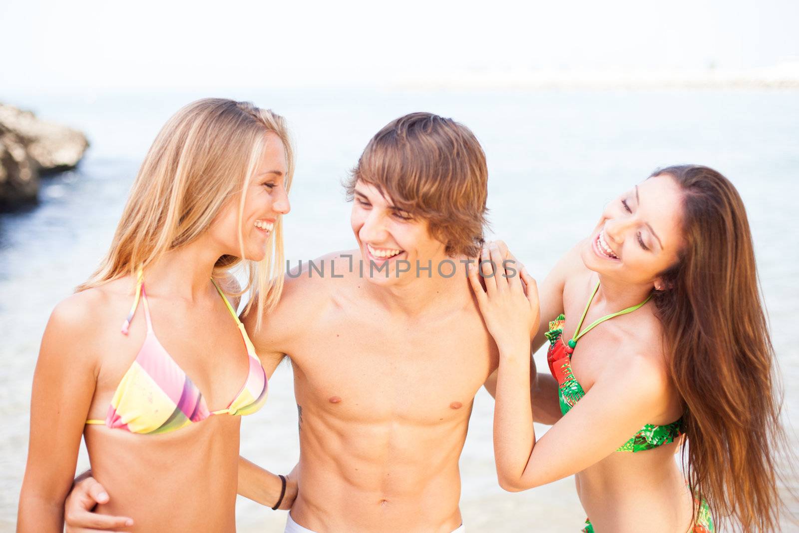 three young beautiful friends having fun on the beach by Lcrespi