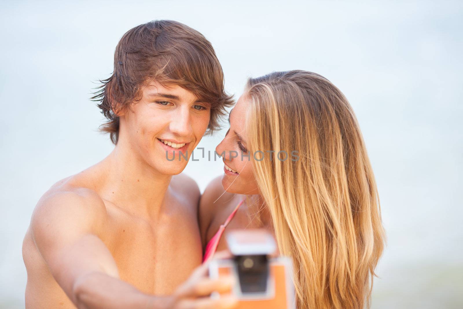 beautiful young couple taking selfie with old camera on the beach by Lcrespi