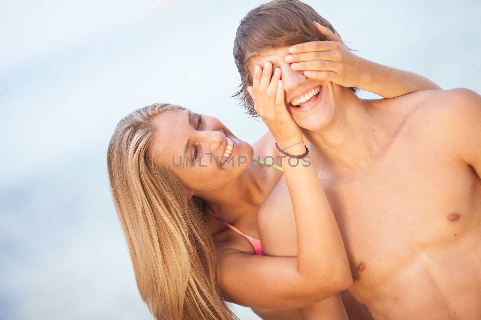 Young couple enjoying themselves at the beach covering eyes by Lcrespi