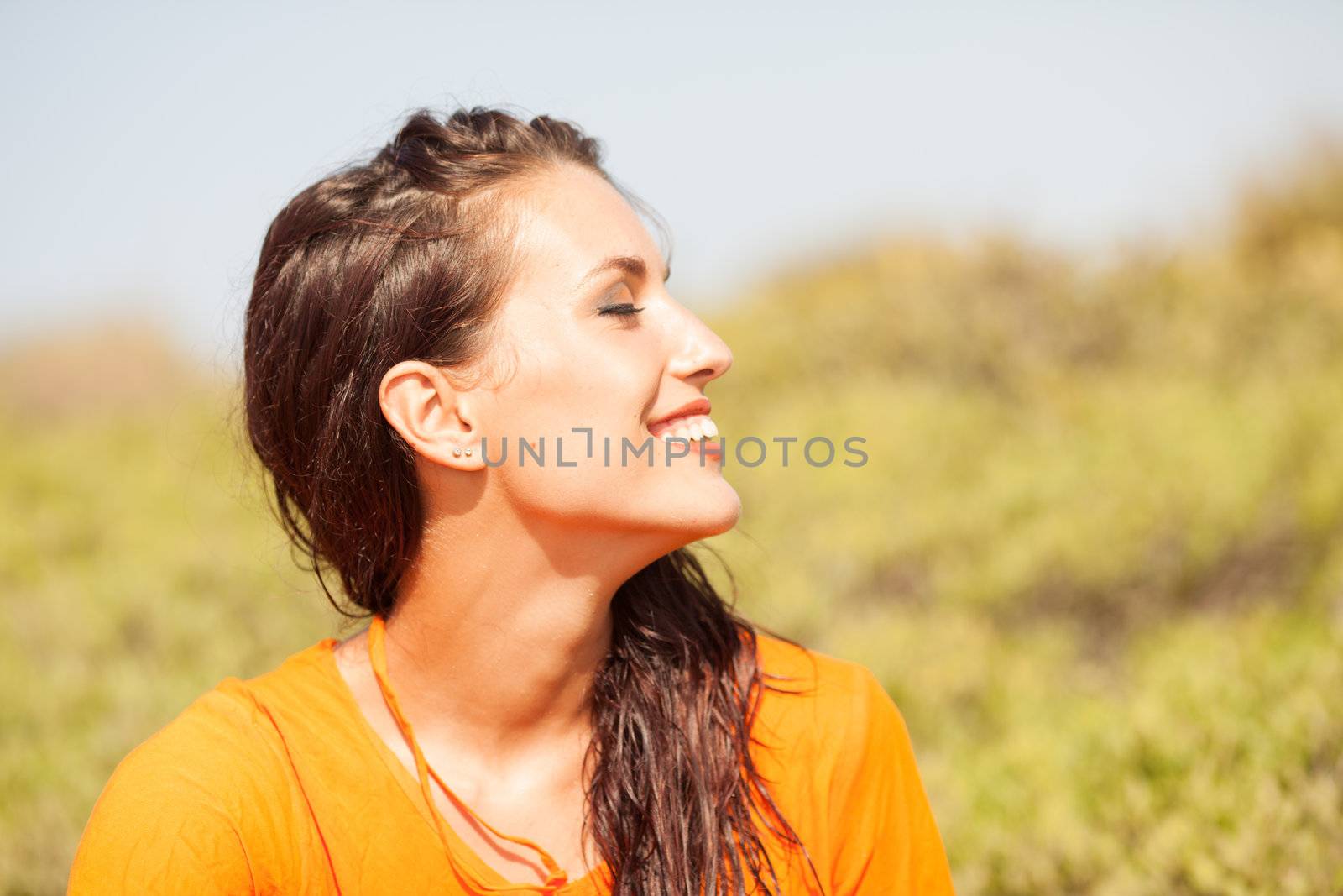 Portrait of young beautiful woman laughing wearing orange shirt