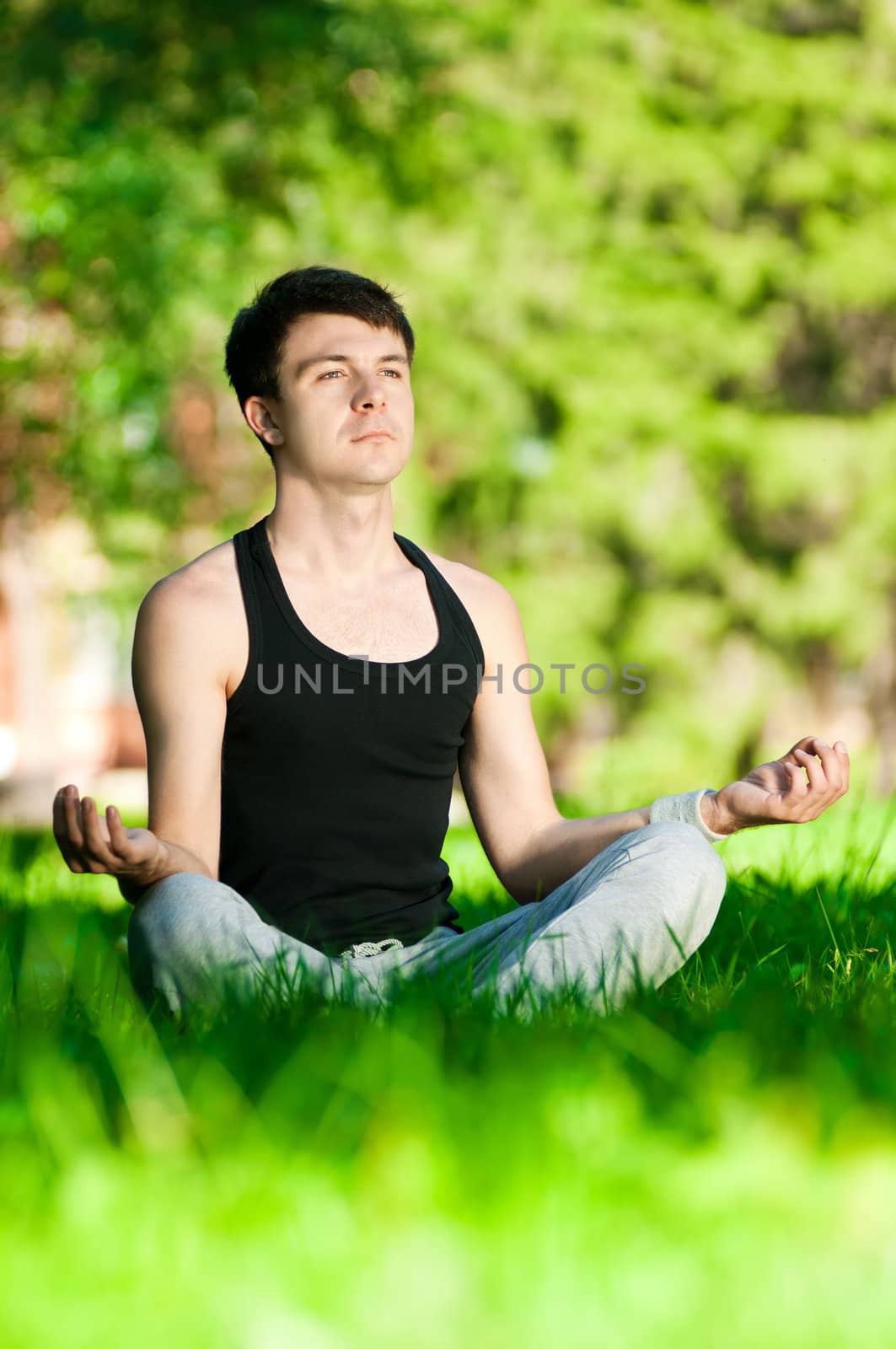 A young man doing yoga exercise by markin