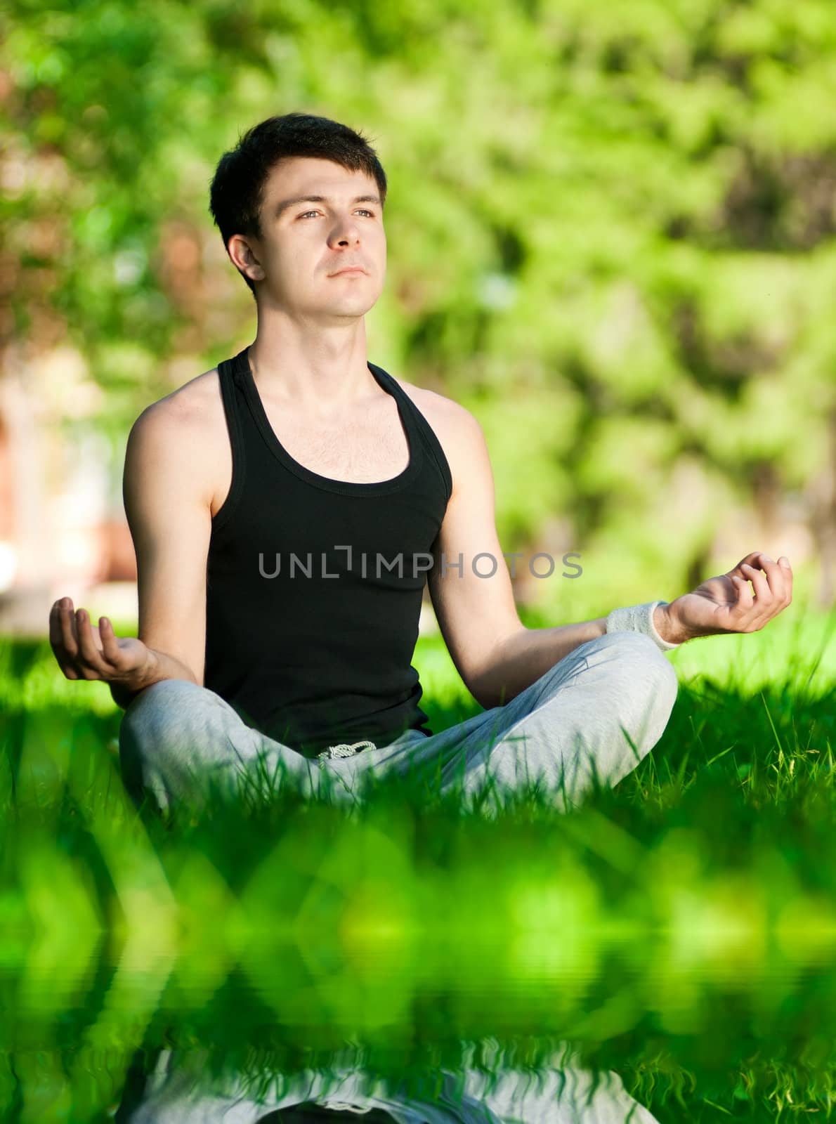 A young man doing yoga exercise by markin