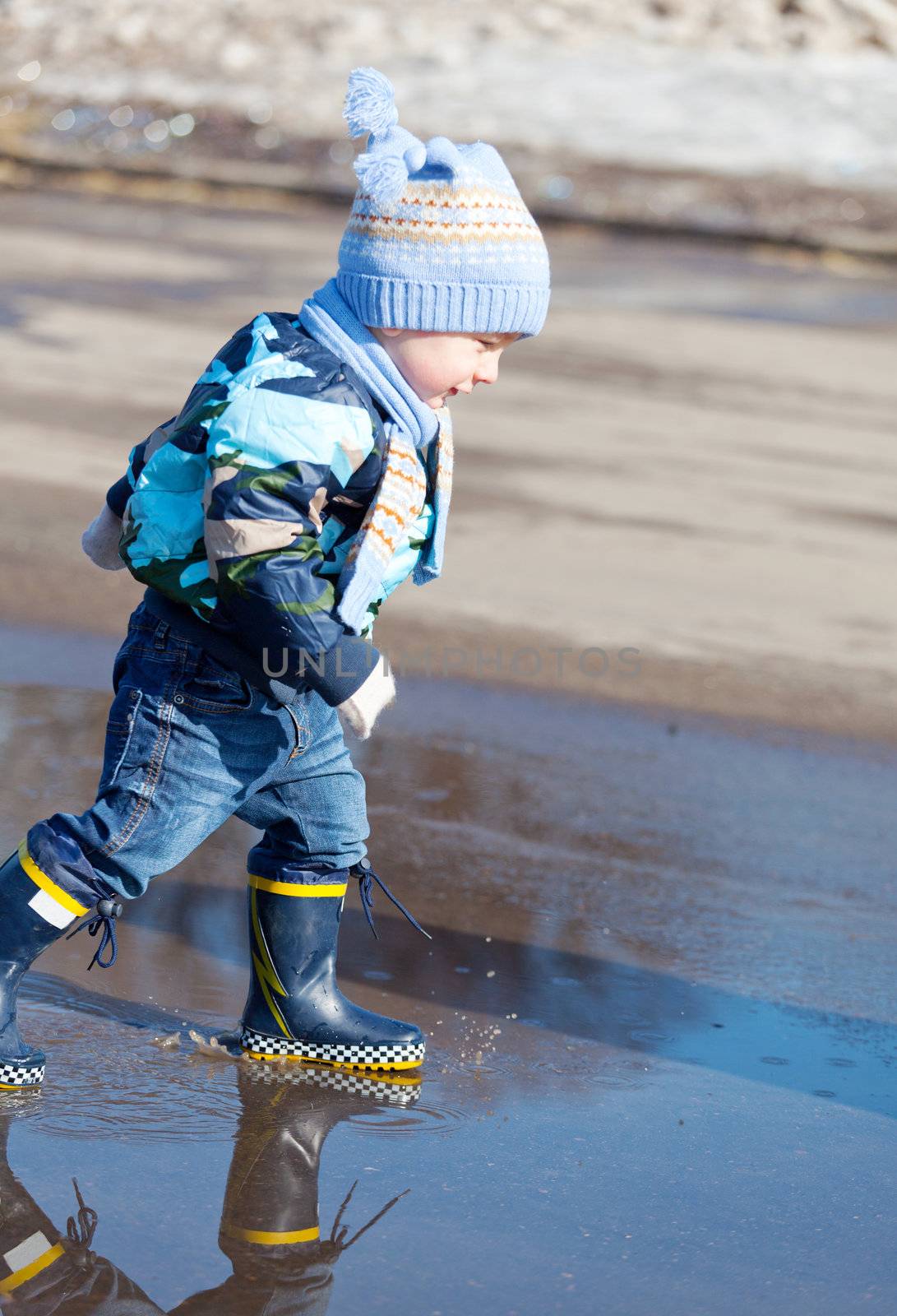 Little boy goes on a pool in rubber boots