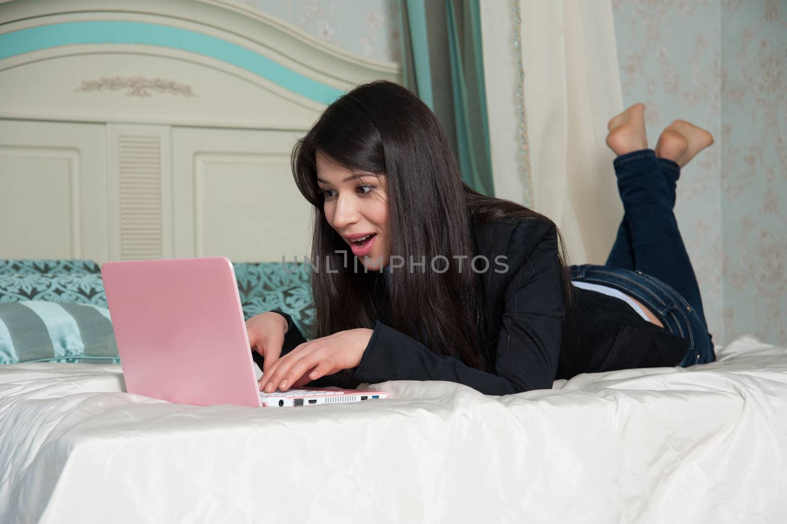  woman lying on the bed with laptop by raduga21