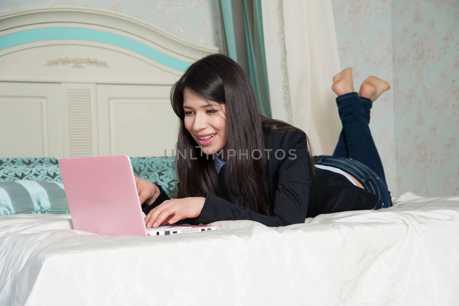 beautiful woman lying on the bed with laptop