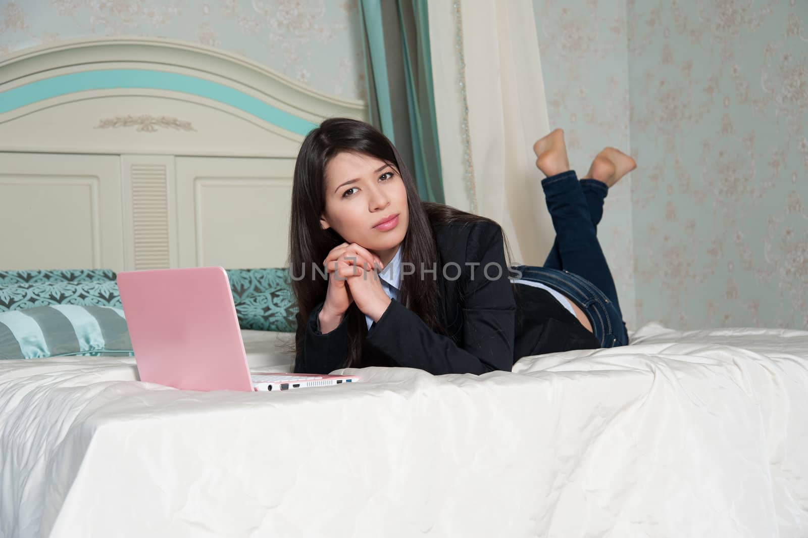  woman lying on the bed with laptop by raduga21