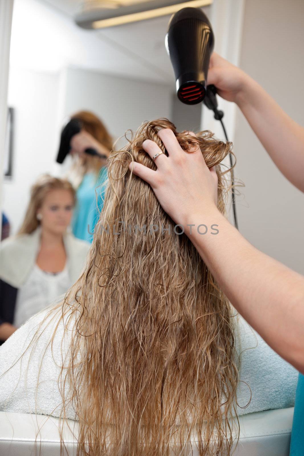 Beautician blow drying woman's hair at parlor