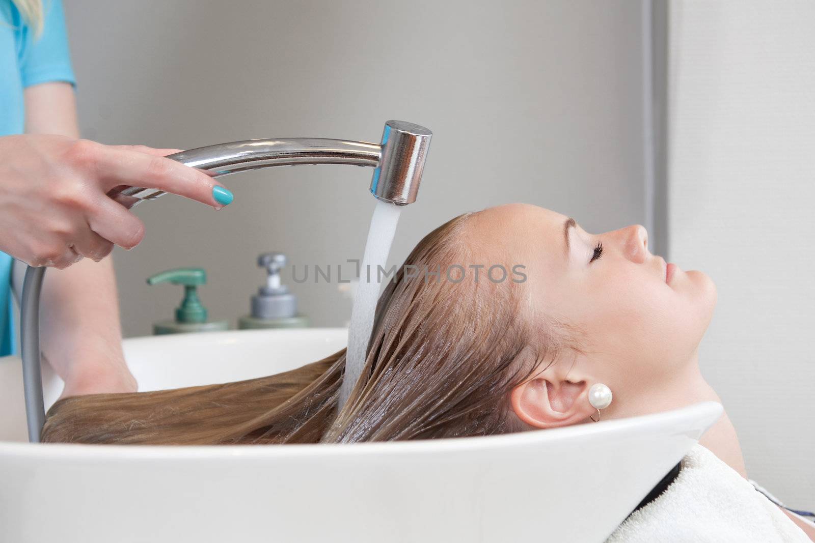 Young female soman having her hair washed and rinsed in beauty salon