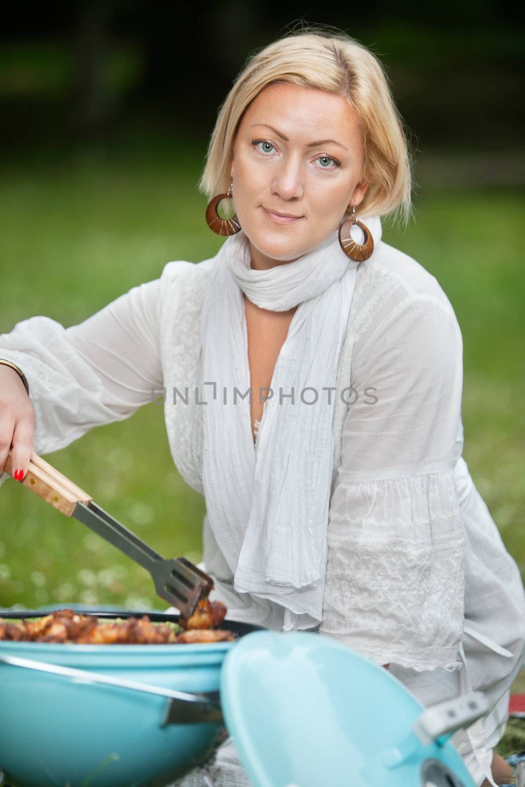 Portrait of an attractive woman in casual wear cooking food on portable barbecue