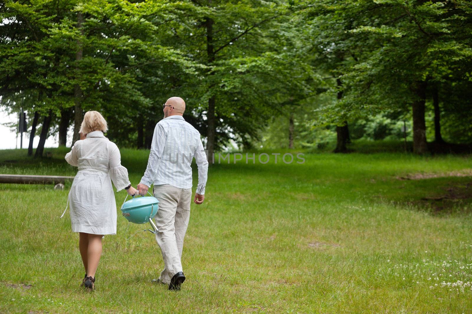 Couple Walking With Portable Barbecue by leaf