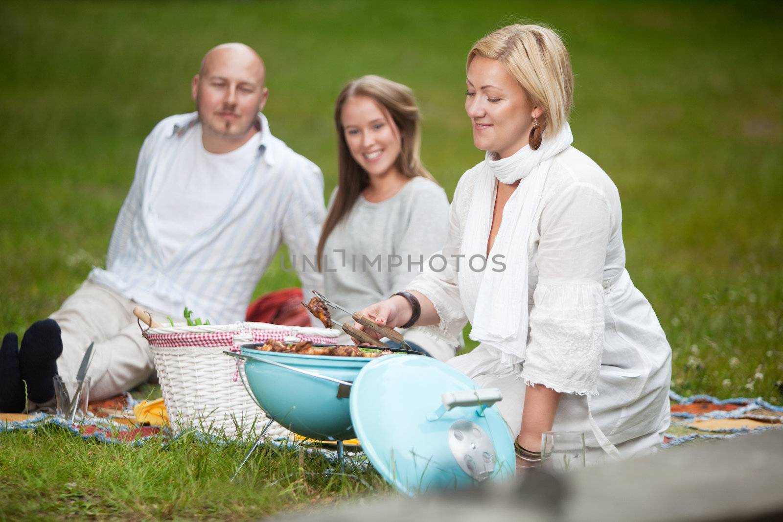 A happy group of friends eating a bbq picnic in the park