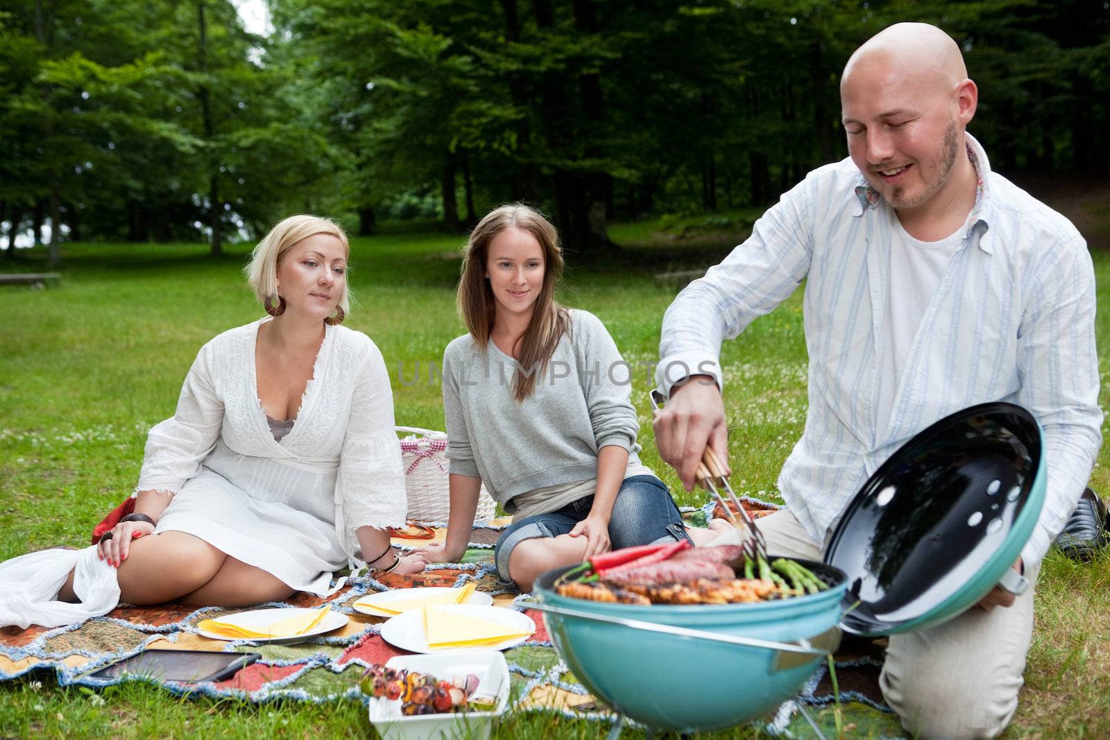 Friends with BBQ picnic in Park by leaf