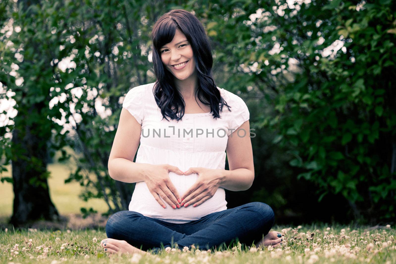 Portrait of a happy young pregnant woman in her third trimester - image has a cross processed style