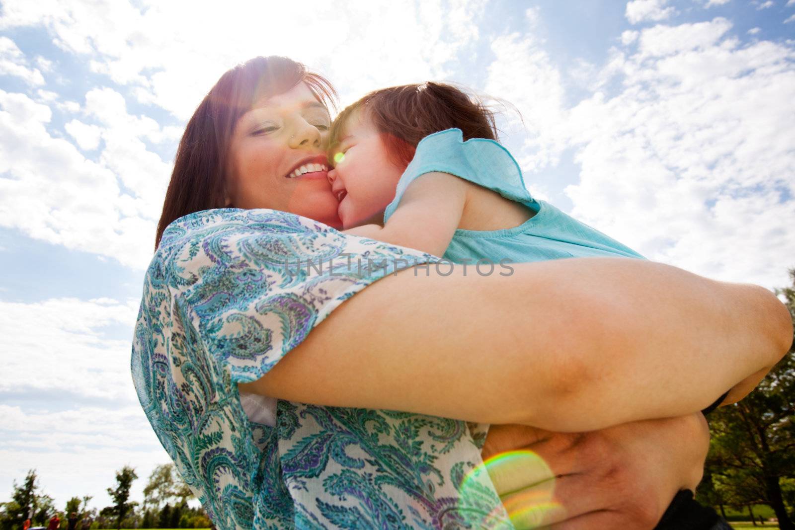 Mother and Daughter Hugging Outdoors by leaf