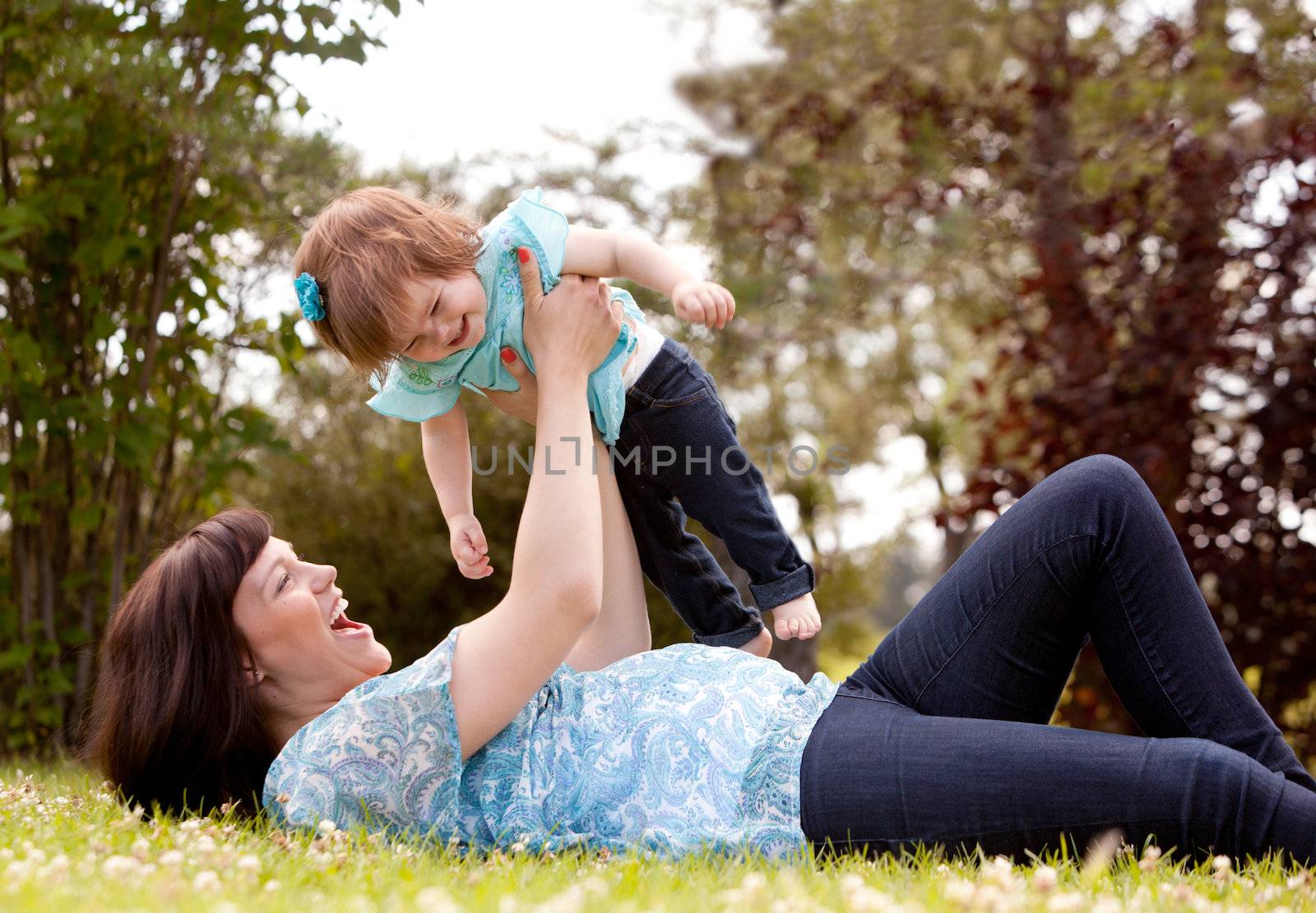 Mother and Daughter Playing in Park by leaf