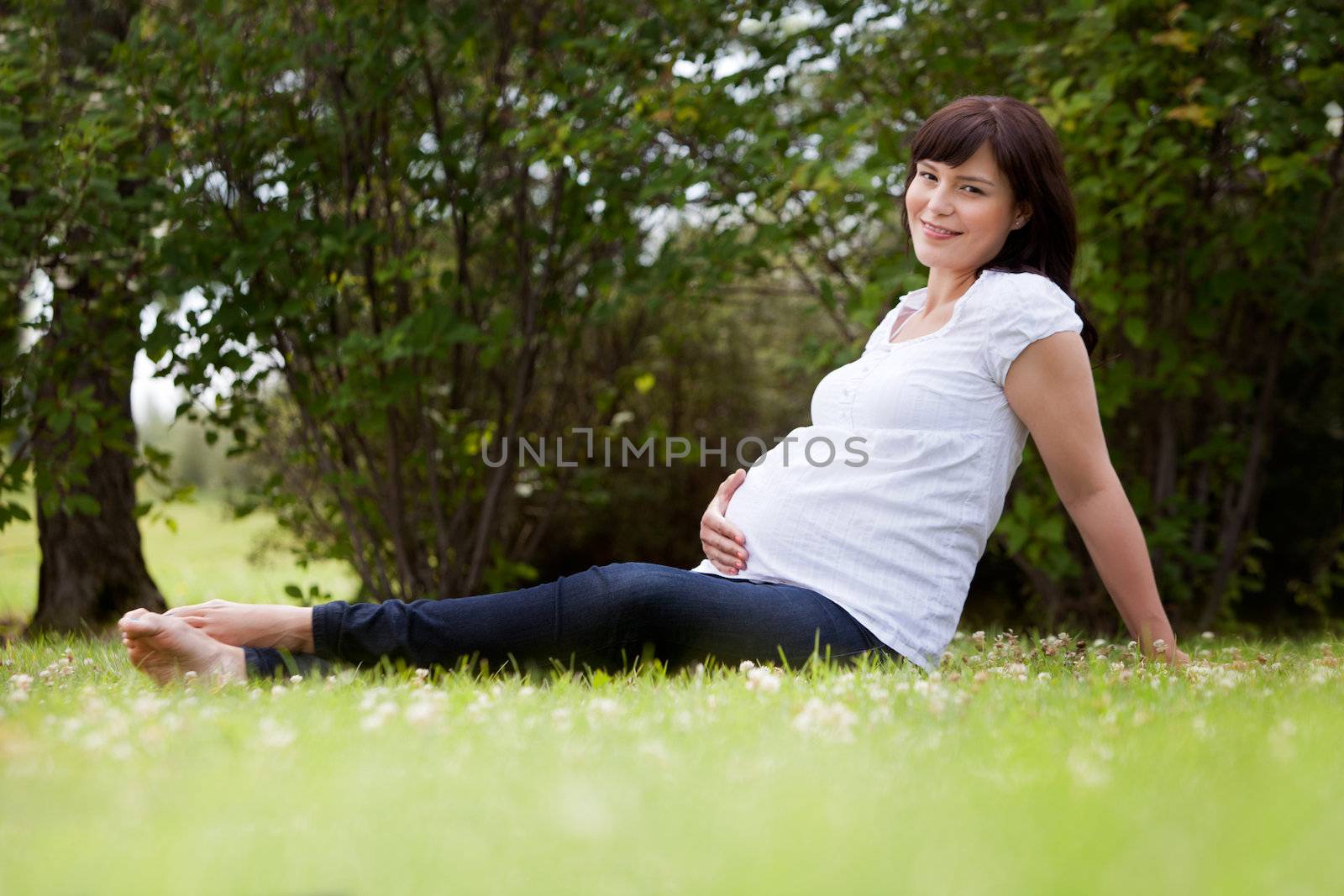 Portrait of a pregnant woman in third trimester relaxing in park