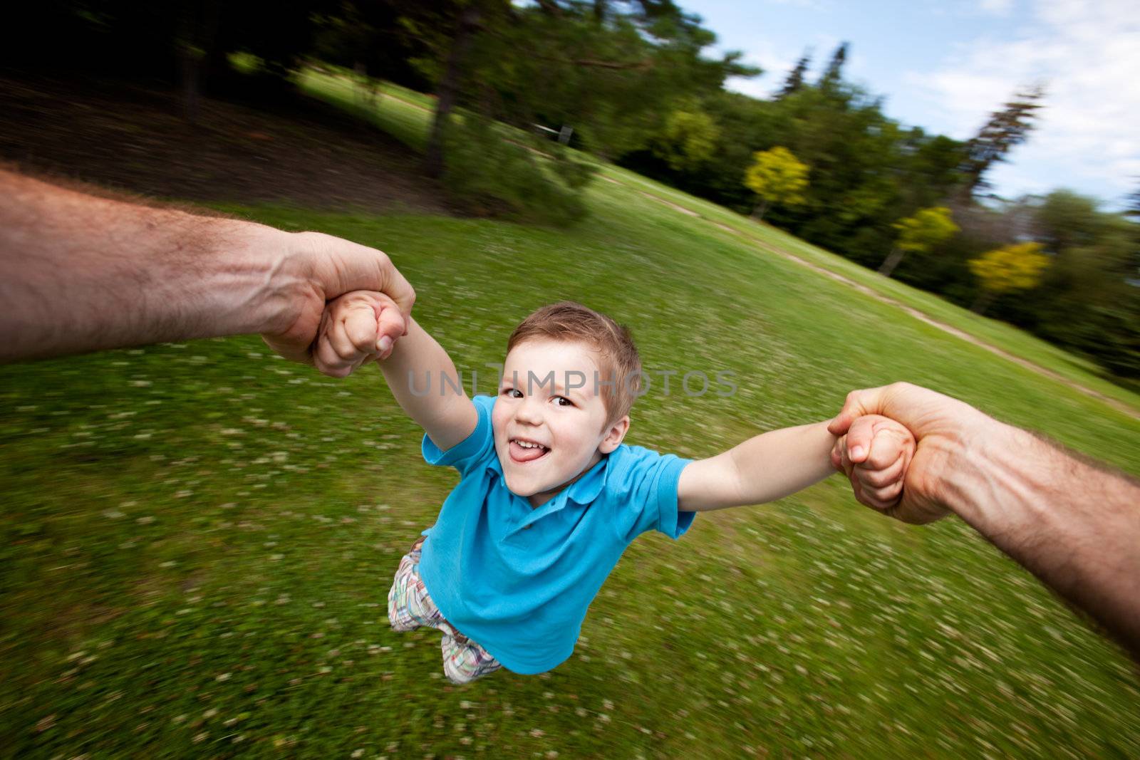 Father Spinning Son Outdoors in Park by leaf