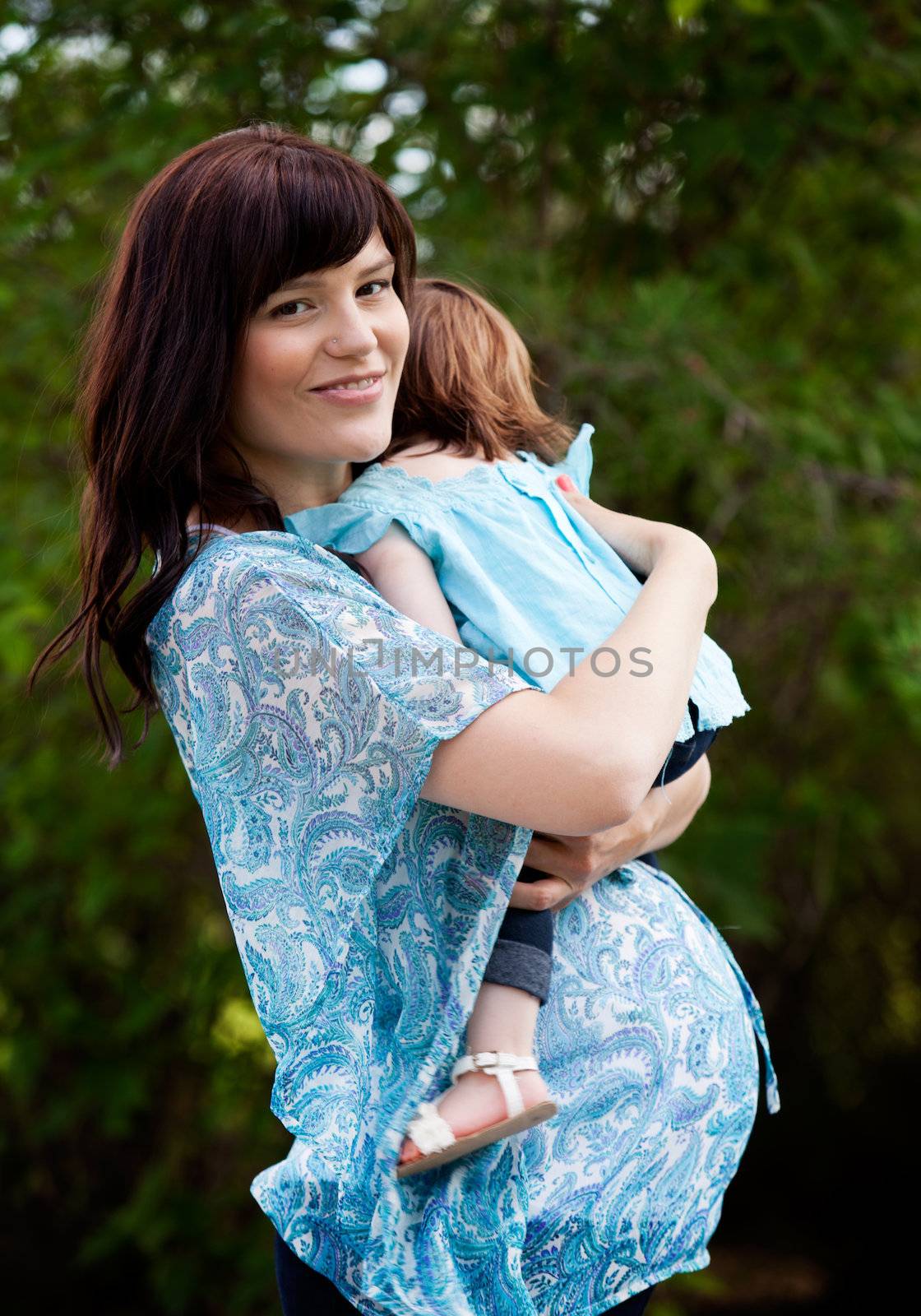 Happy pregnant mother with toddler daughter in park