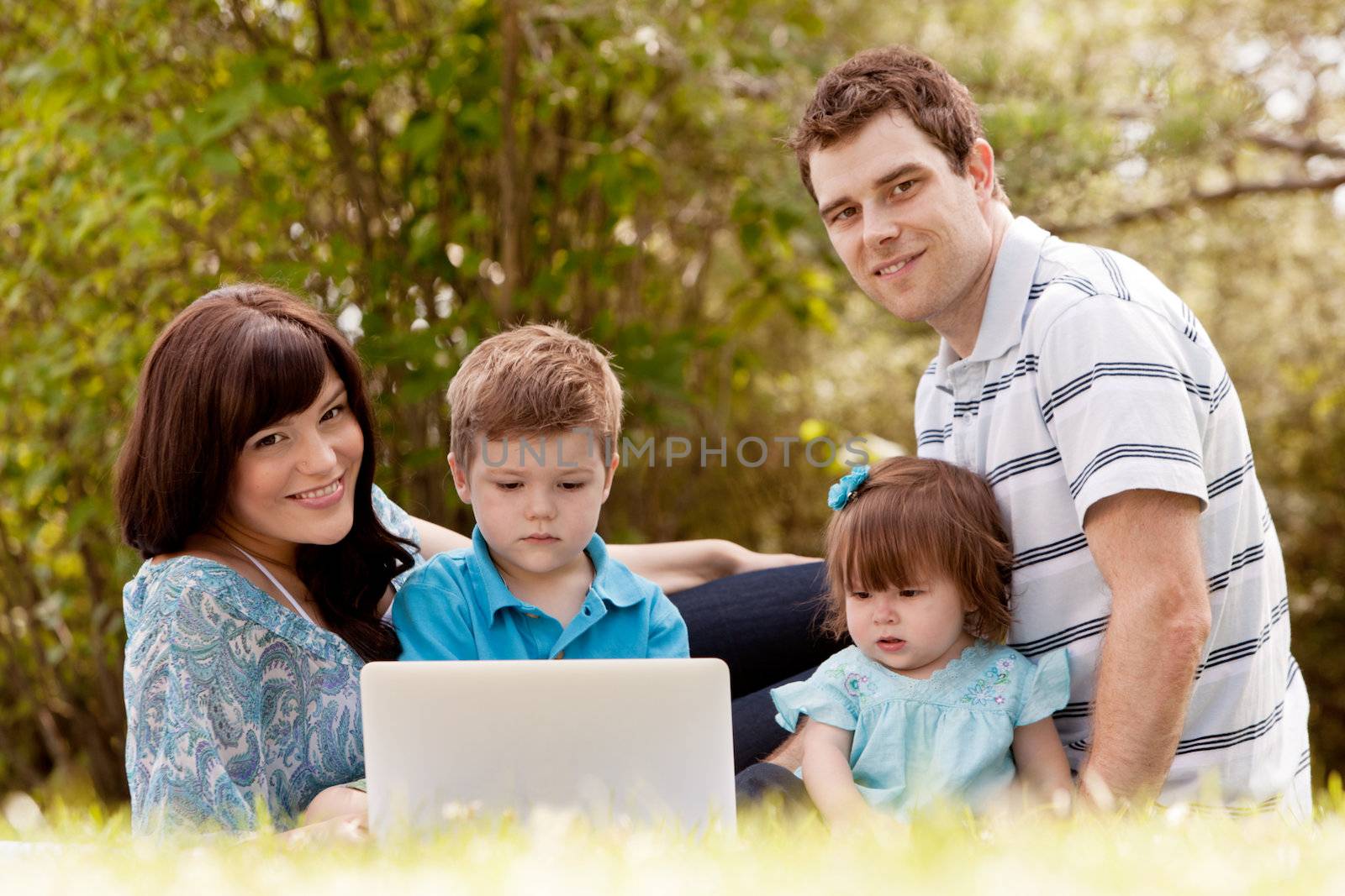 Portrait of happy family outdoors with laptop computer