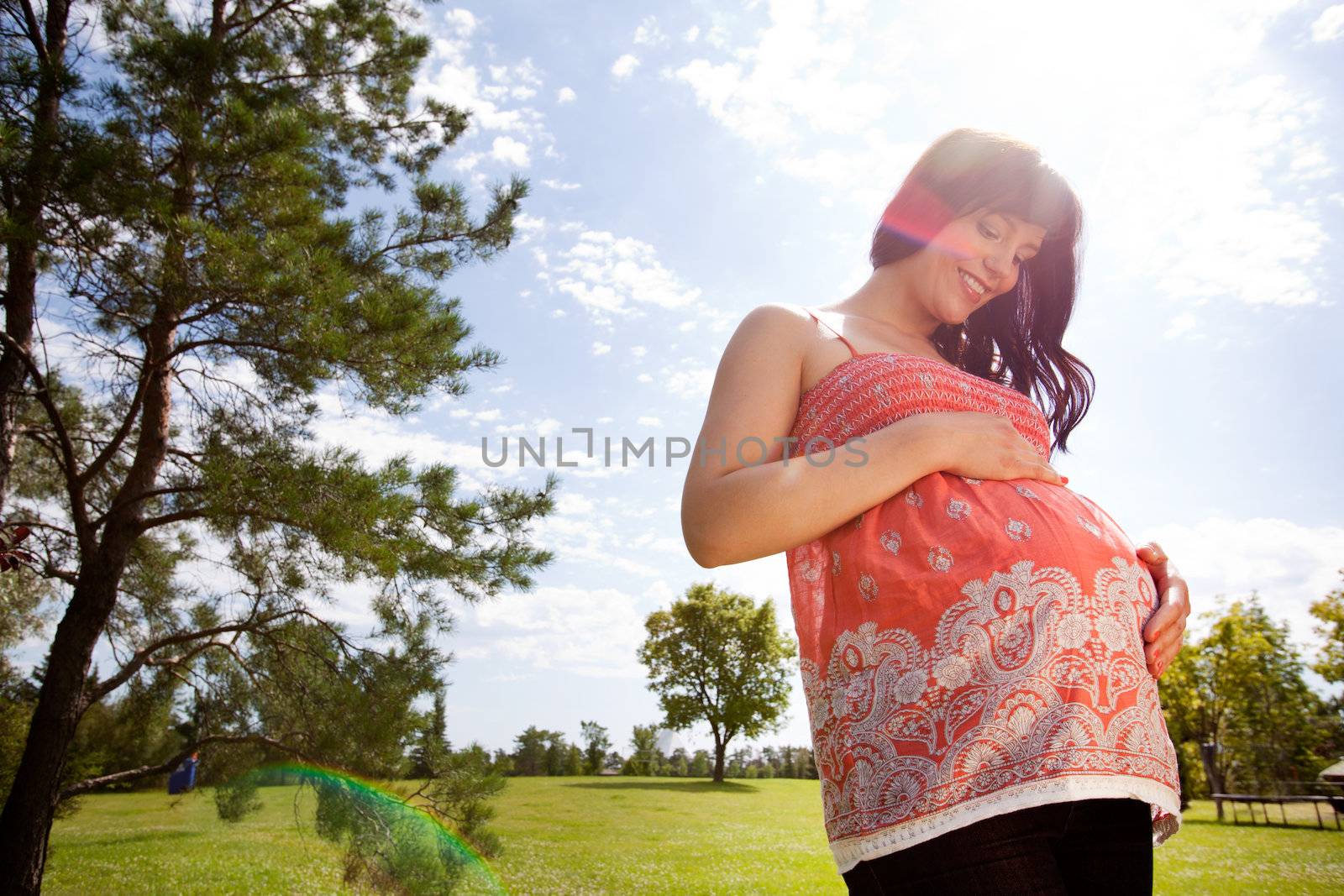 Happy Pregnant Woman in Park by leaf