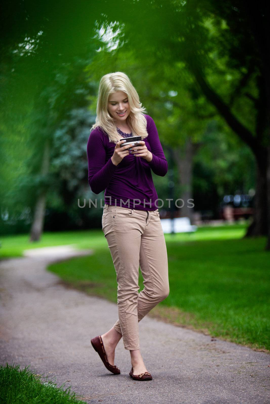 Woman standing in park writing text message