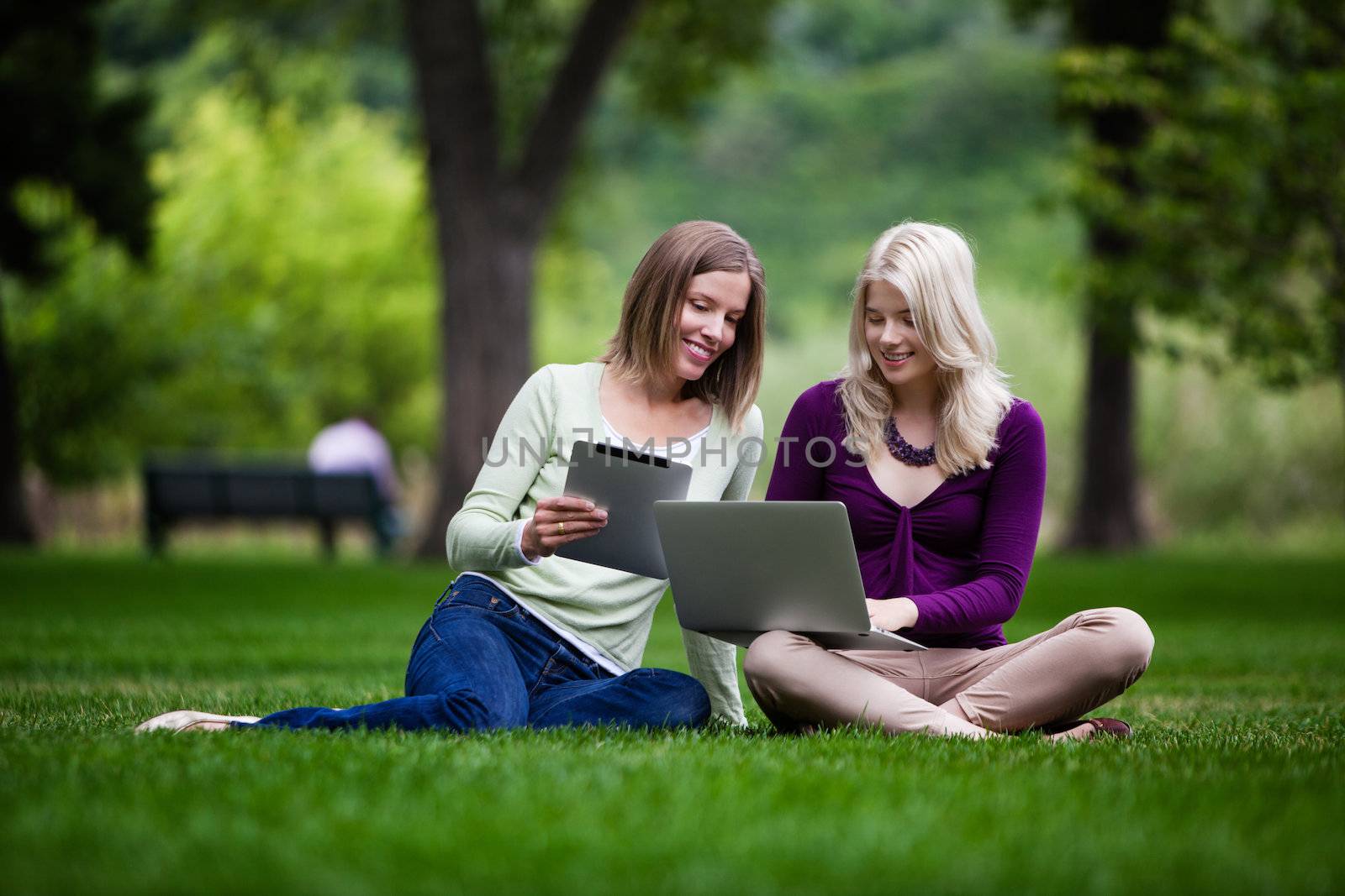 Two young women using tablet computer and laptop together