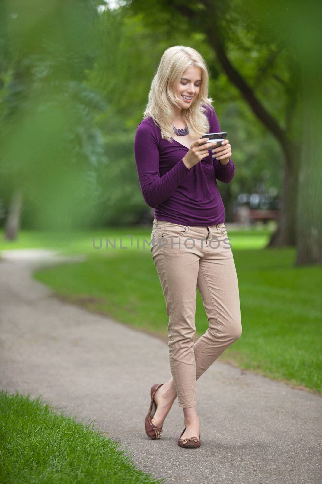 Woman Using Smart Phone In Park by leaf