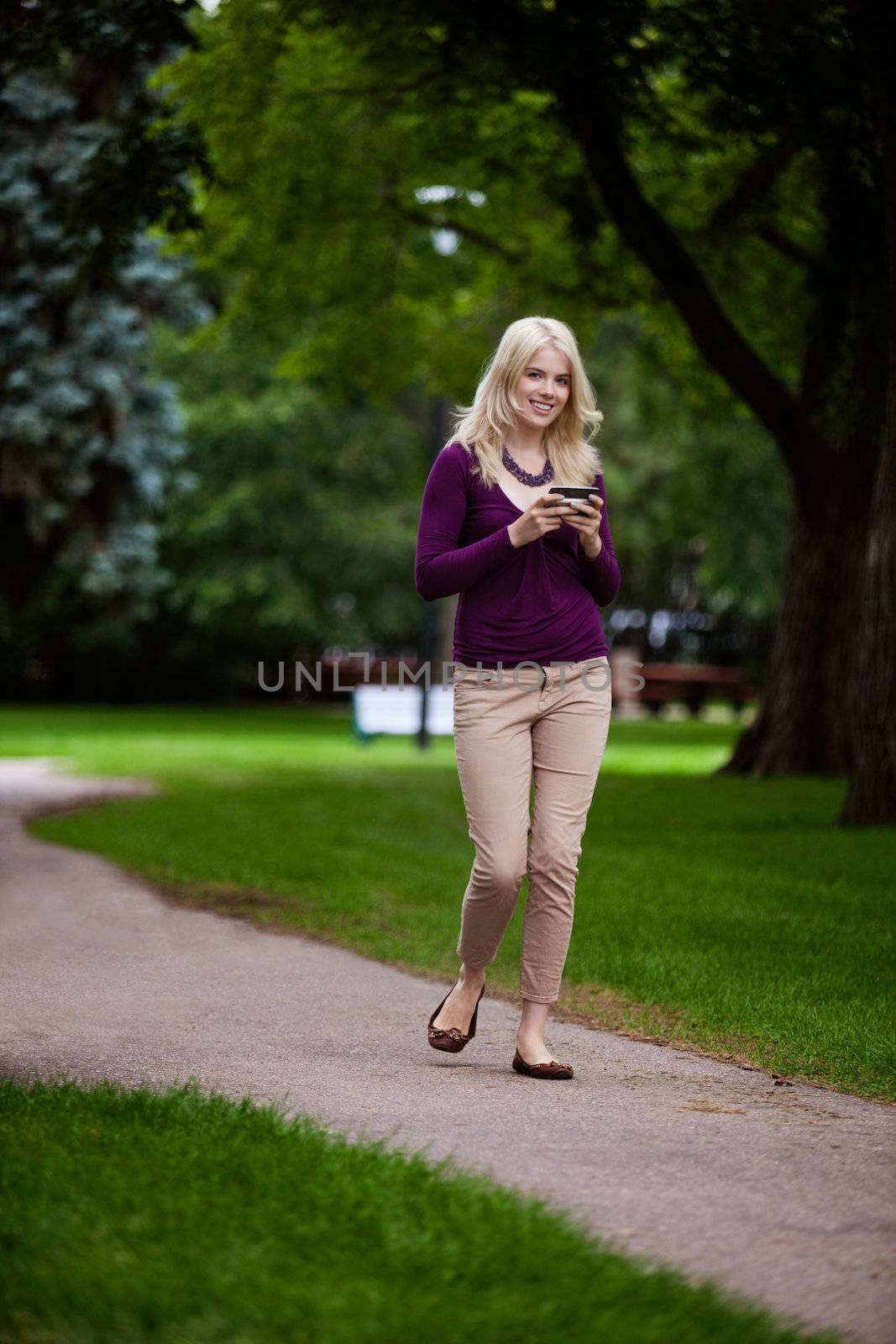 Woman in park looking at camera using cell phone