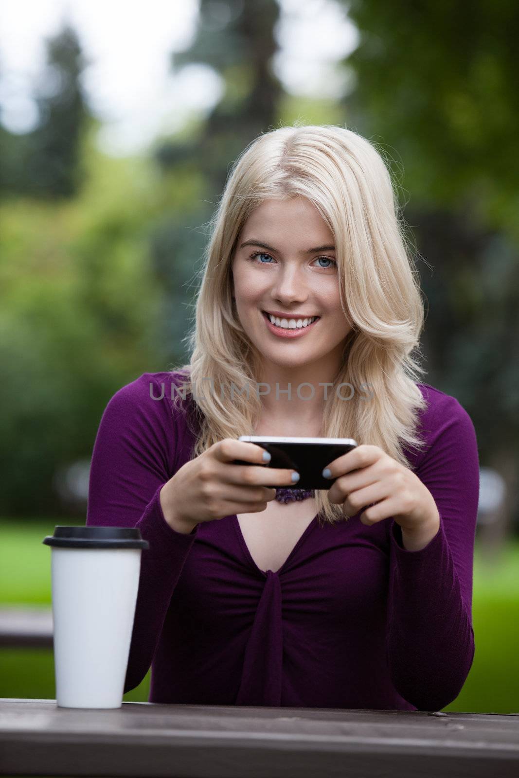 Portrait of a smiling woman using a mobile phone in park