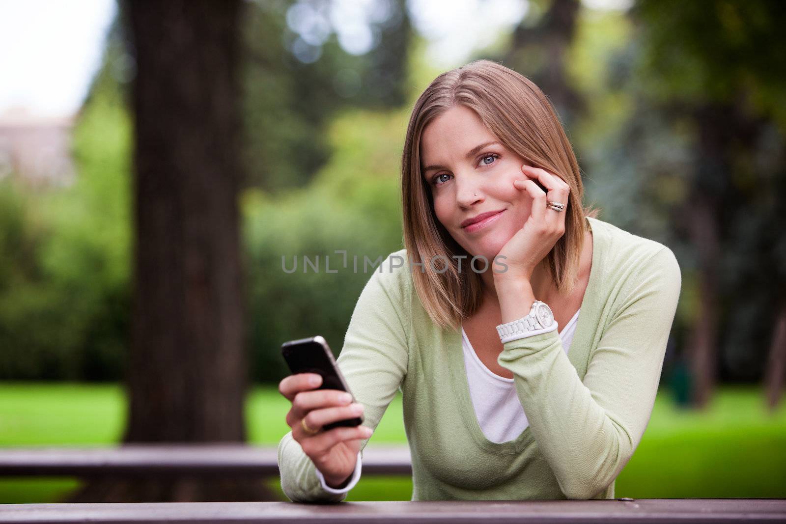 Woman holding Cell Phone in park.