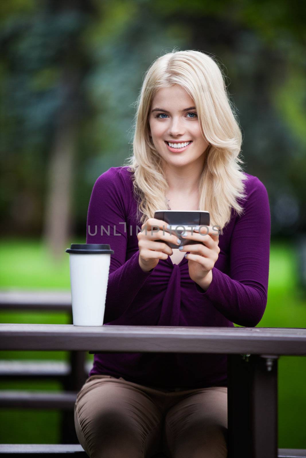Young college student in park with phone and coffee