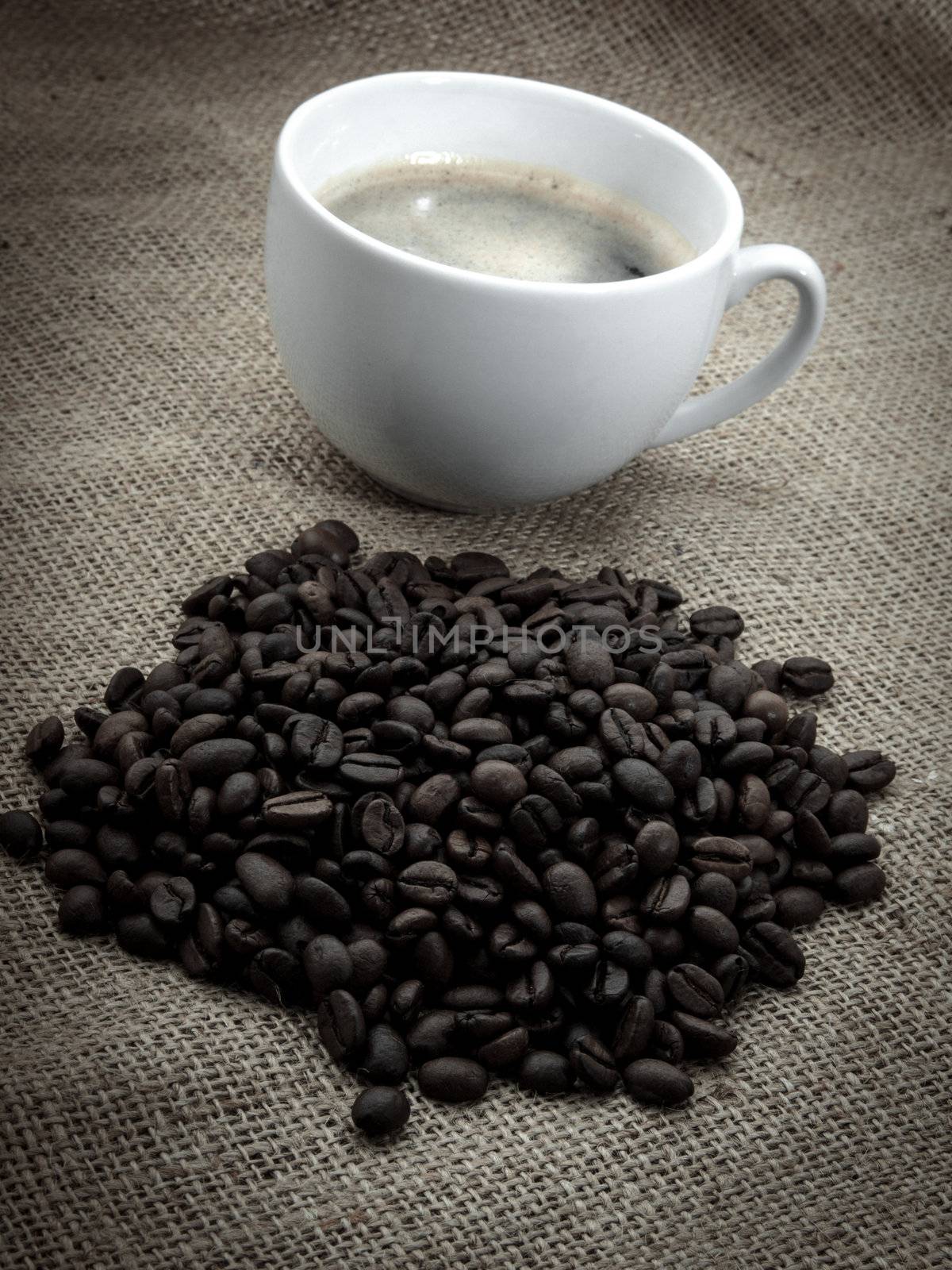 Black coffee bean with coffee cup, over old burlap background