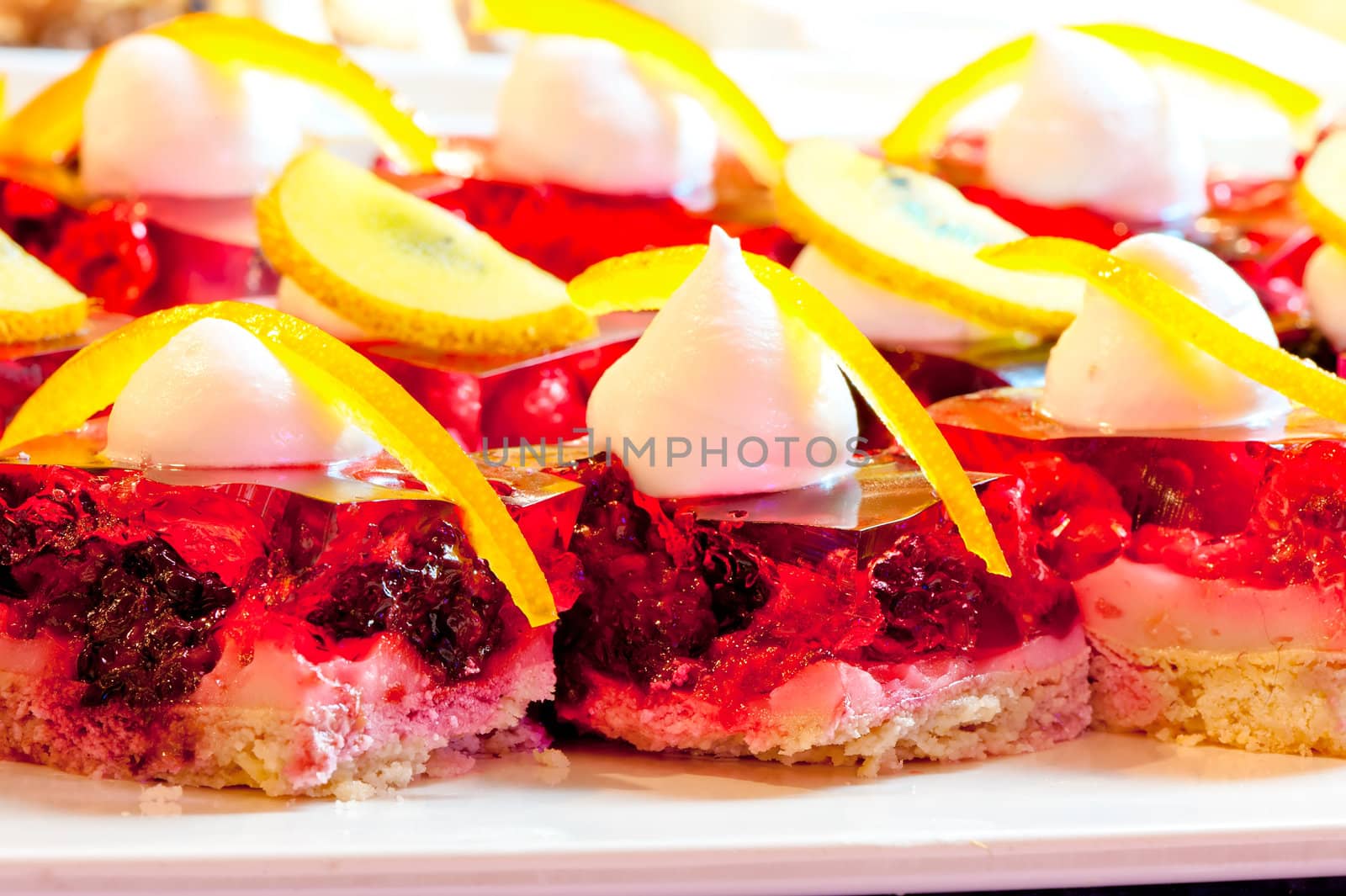 Biscuit dessert with fruit and berry jelly, whipped cream and orange zest