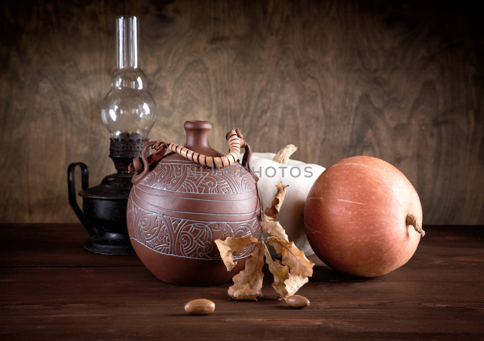 Still-life with a jug an oil lamp and pumpkins on a table