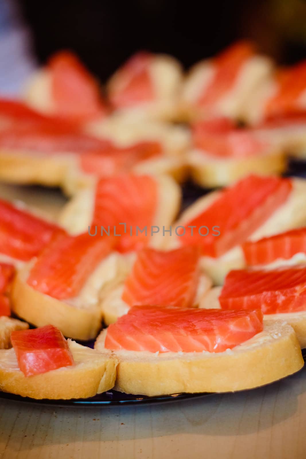 Sandwiches with smoked salmon and arugula on a black plate and wooden board