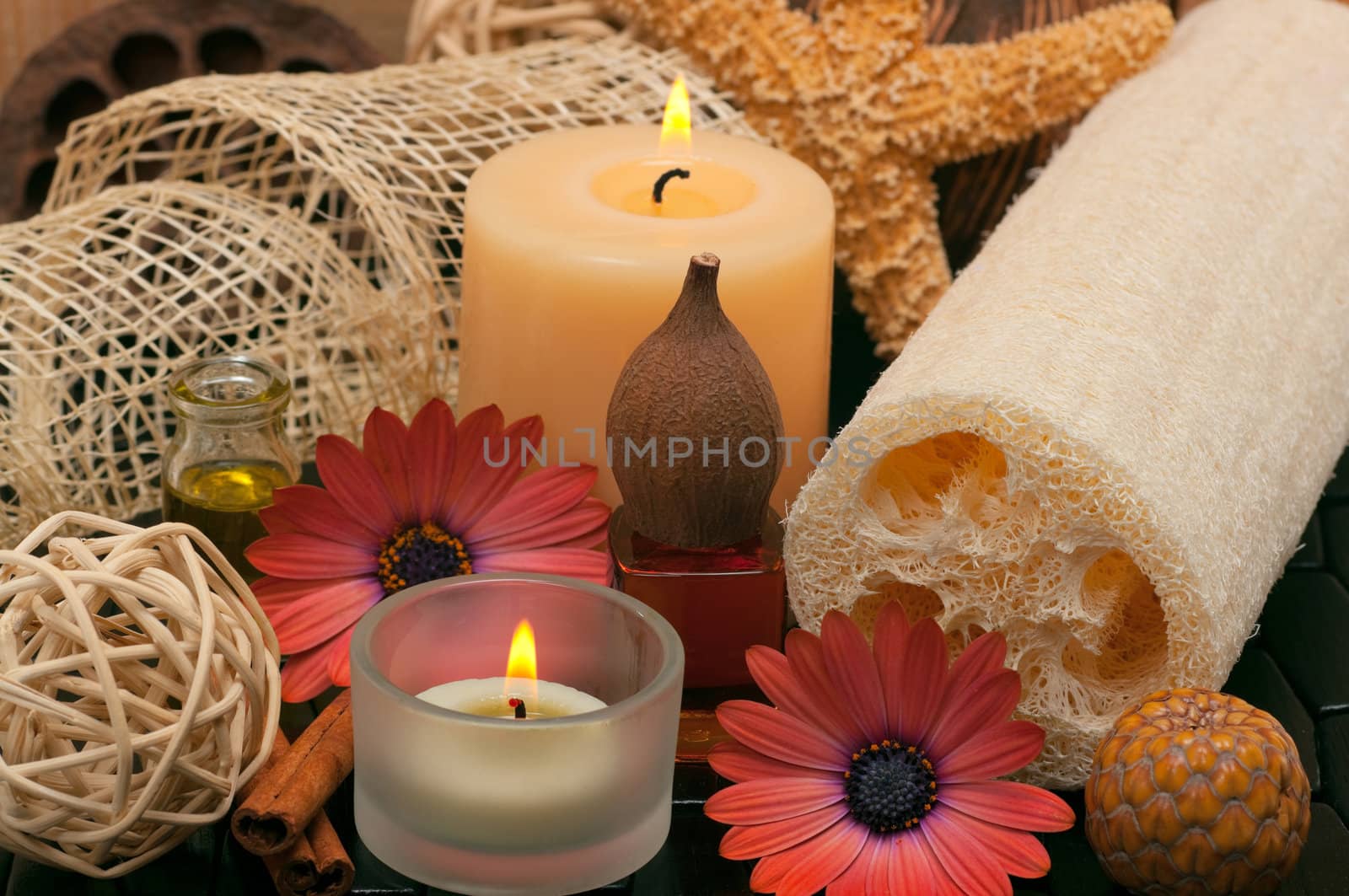 Spa concept with aromatic candles, herbs, beautiful daisies, massage oil and loofah 