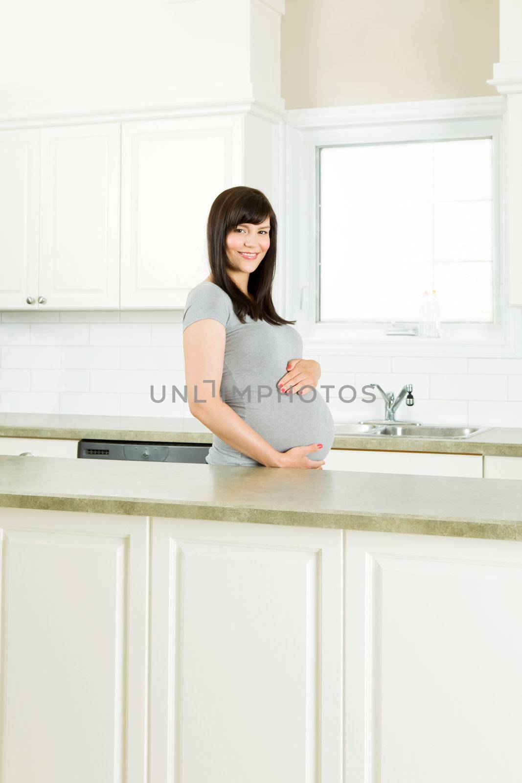 Healthy pregnant woman standing in kitchen behind counter