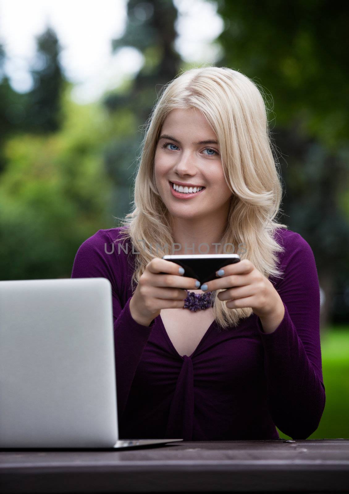 Portrait of smiling young female holding smart phone