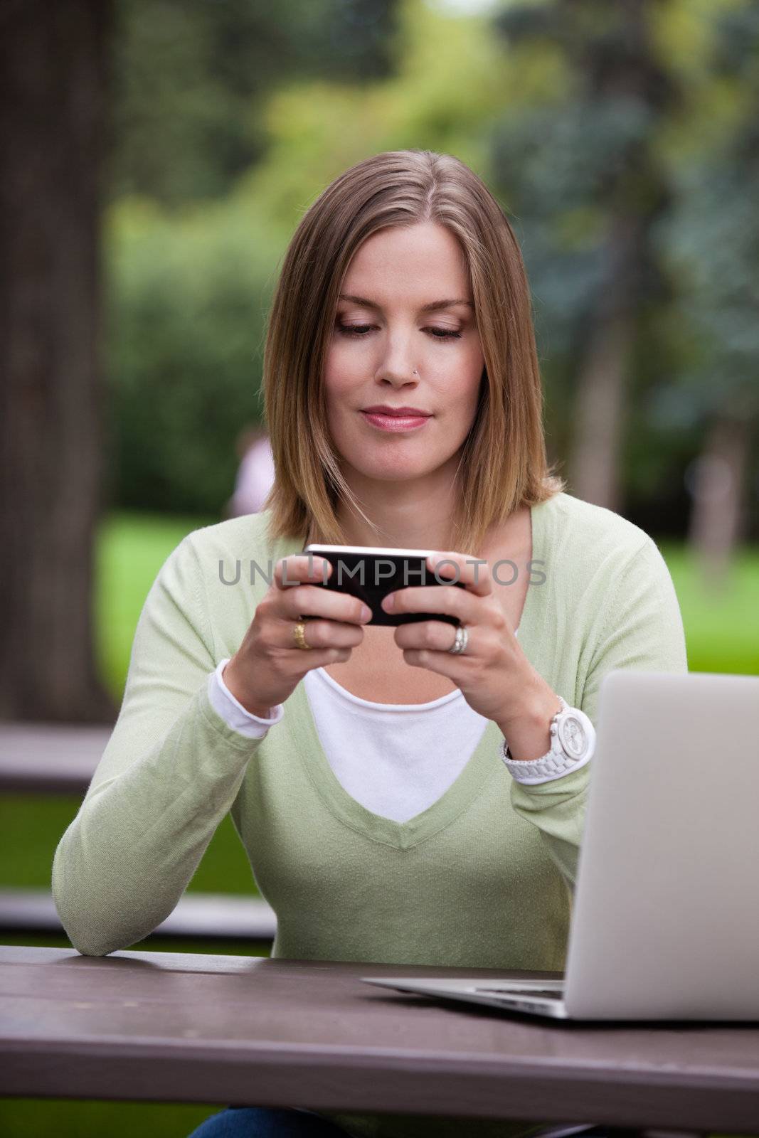Woman creating a status update with mobile phone in park
