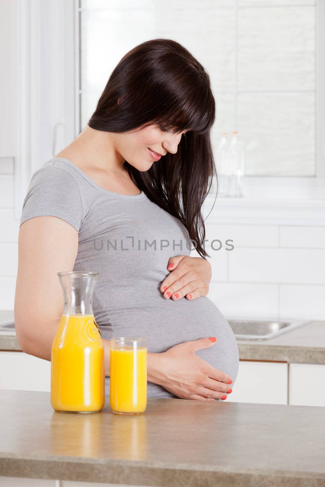 Happy pregnant woman in third trimester in kitchen at home