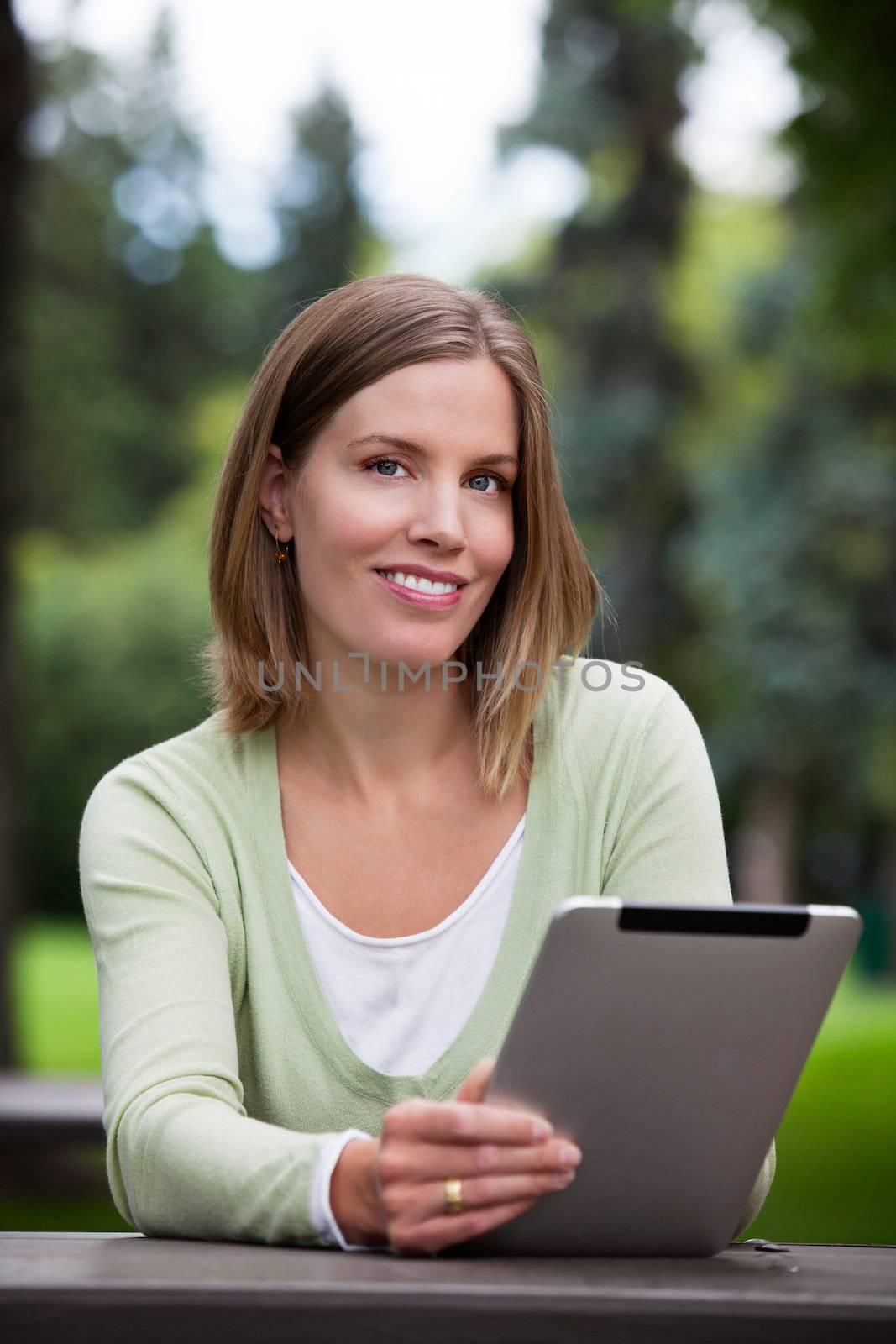 Woman holding Digital Tablet in park.