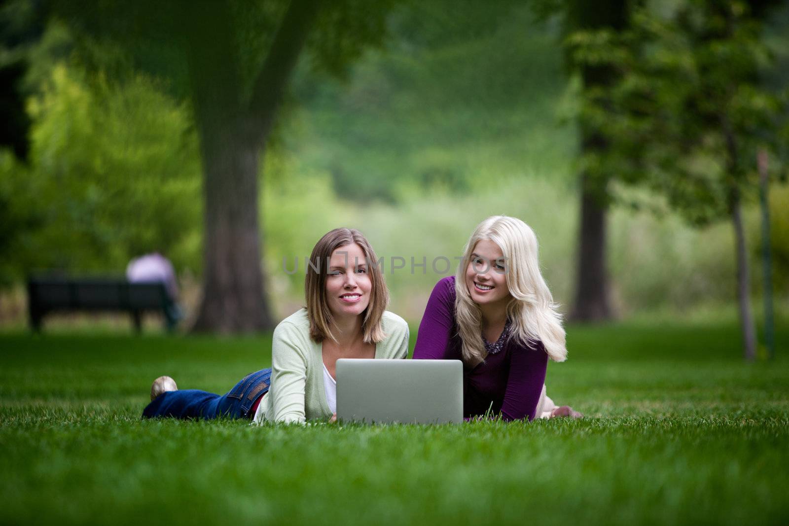 Young women using laptop in park, looking at camera